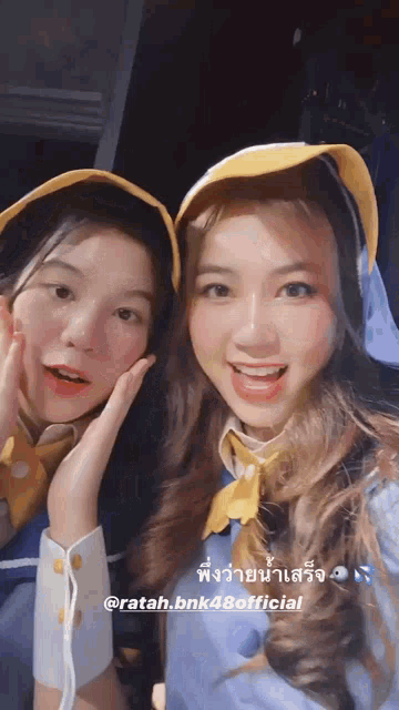 two girls are posing for a picture together and one of them is wearing a yellow hat .