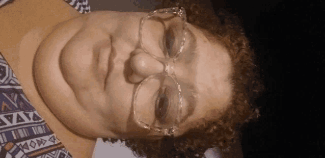 a close up of a woman wearing glasses and a shirt with a pattern