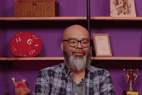 a man with glasses and a beard stands in front of a purple wall with a sign that says " kill them "