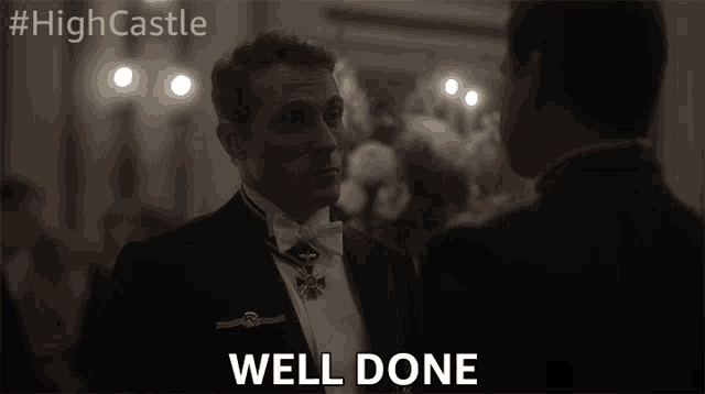 a man in a tuxedo says well done in front of another man