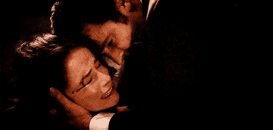 a man and a woman are hugging each other in a dark room and the woman is crying .