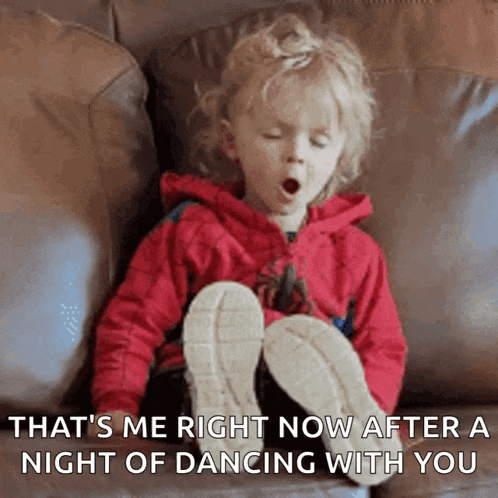 a little girl is yawning while sitting on a couch with her legs crossed