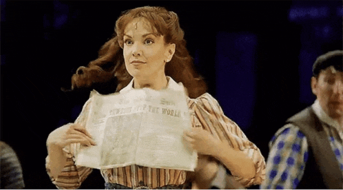a woman in a striped shirt is holding a newspaper .