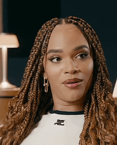 a woman with braids is wearing a white shirt with a cc logo on it