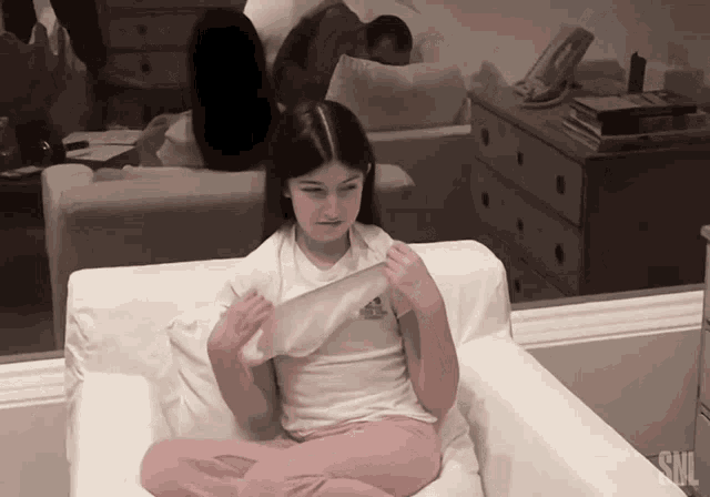 a little girl is sitting in a chair with snl written on the bottom right