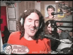 a man wearing headphones is standing in front of a microphone in a room .