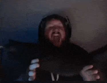 a man with a beard and headphones is holding something in his hands in a dark room .