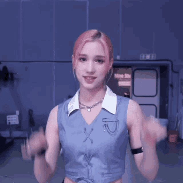 a woman with pink hair is making a heart shape with her finger