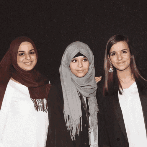 three women are posing for a picture and one has a microphone in her hand