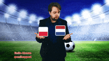 a man in a suit holds up two flags in front of a soccer field