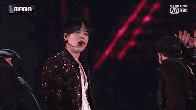 a man in a sequined jacket is dancing on a stage with a microphone .