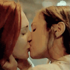 a couple of women are kissing each other in a room .