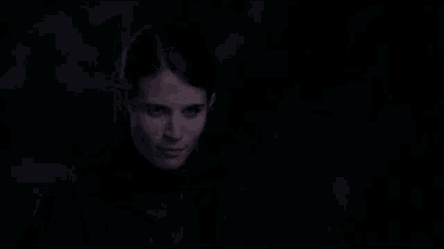 a woman is smiling in the dark and wearing a black shirt
