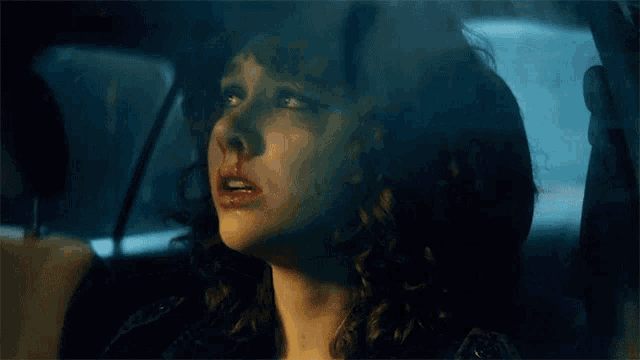 a woman with a bloody nose is sitting in a car at night