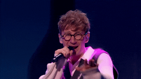 a man singing into a microphone with glasses on