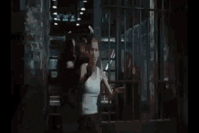 a man and a woman are standing in a prison cell .