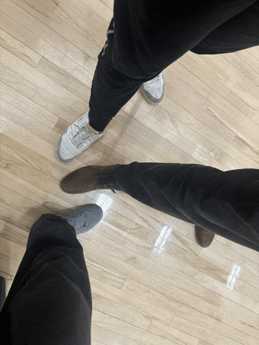 a person standing on a wooden floor wearing a pair of white shoes
