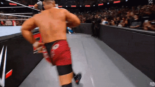 a wrestler is running down the ring during a wrestling match
