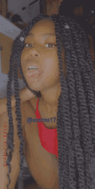 a girl with long hair is wearing a red tank top and has the number 17 on her shoulder