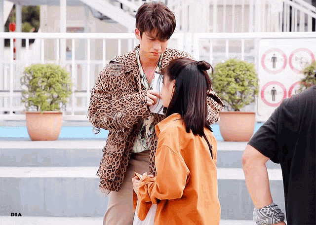 a man in a leopard print jacket talks to a woman