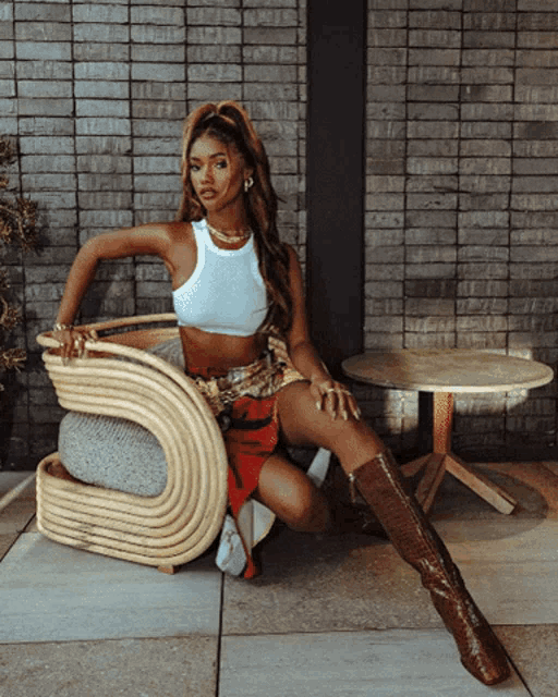 a woman in a white tank top sits in a chair