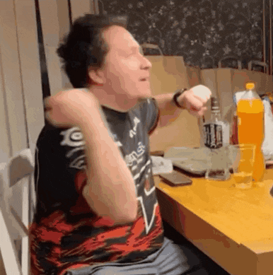 a man is sitting at a table with his arms in the air