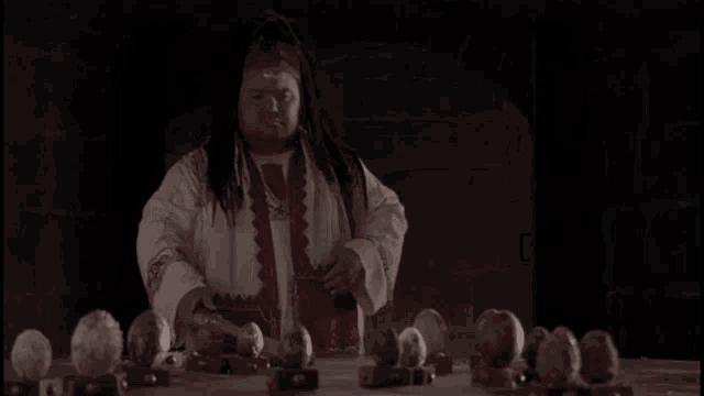 a man in a white and red robe is standing in front of a table filled with eggs .
