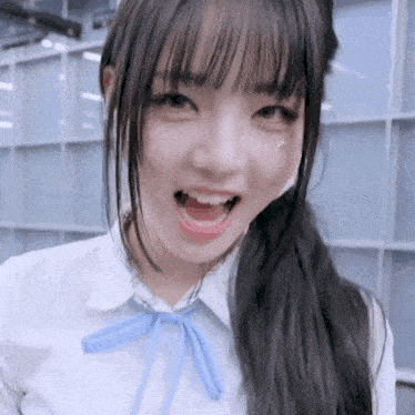 a close up of a girl with her mouth open wearing a white shirt and blue bow tie .