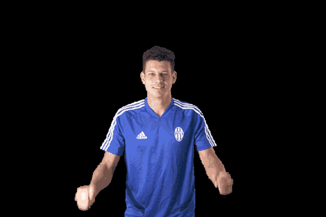 a man wearing a blue adidas shirt is cheering