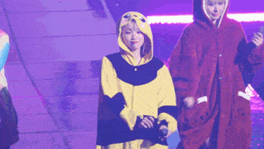 a woman in a bee costume is standing next to another woman in a red coat on a stage .
