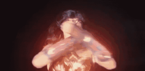a woman in a wonder woman costume is standing in the dark holding a sword .