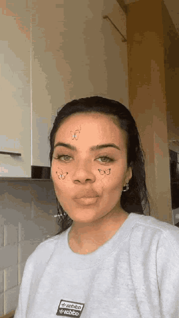 a woman with butterflies on her face wearing an adidas shirt