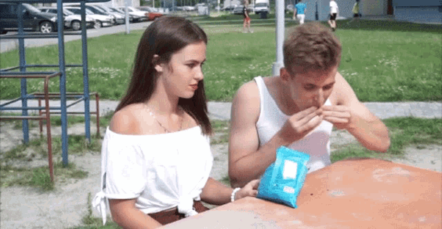 a boy and a girl are sitting at a table with a bag of chips on it