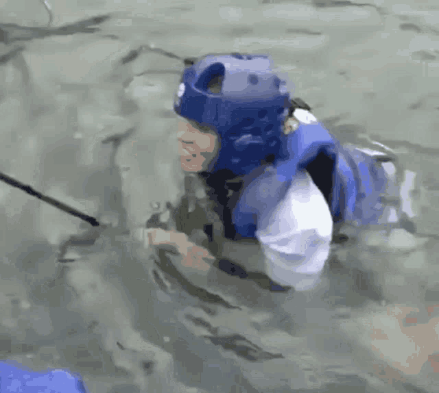 a man wearing a blue helmet is swimming in the water