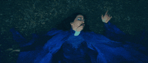 a woman in a blue dress is laying down with her arms outstretched