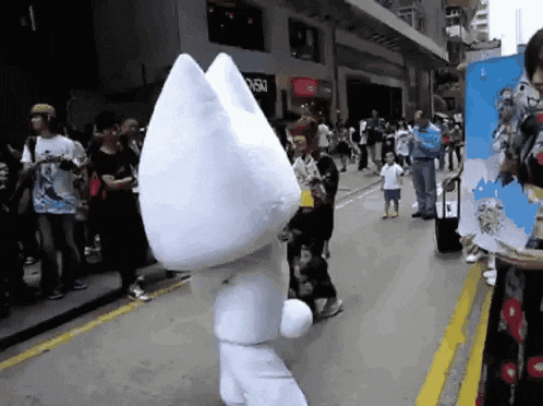 a white cat mascot is walking down a street in front of a store that says sushi