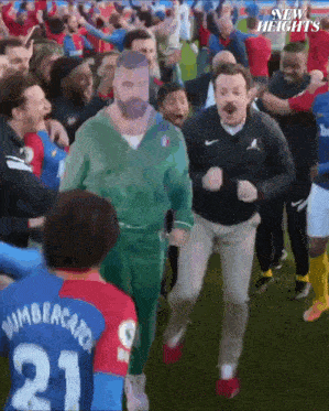 a group of people are dancing on a soccer field and one of the players is wearing a number 21 jersey