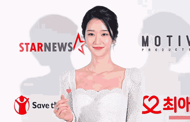 a woman in a white dress stands in front of a sign that says starnews