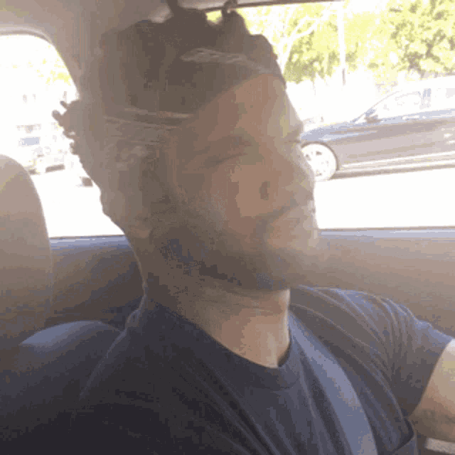 a man with a bandana on his head is sitting in the back seat of a car
