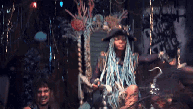 a woman in a pirate costume is sitting in front of a sign that says " life is a pirate "