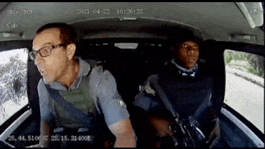 a man with glasses is sitting in the back seat of a car with a gun .