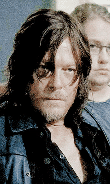 a man with long hair and a beard is wearing a black shirt