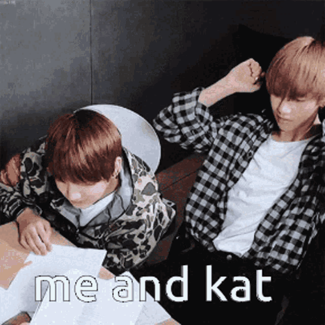 two boys are sitting at a table with the words me and kat written on it