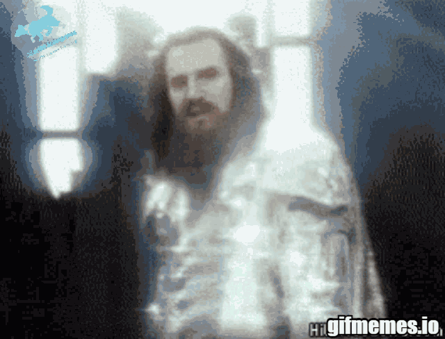 a blurred image of a man with a beard and long hair with the words higifmemes.io on the bottom right