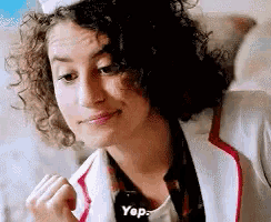 a woman with curly hair is wearing a chef 's hat and a white jacket and says yes .