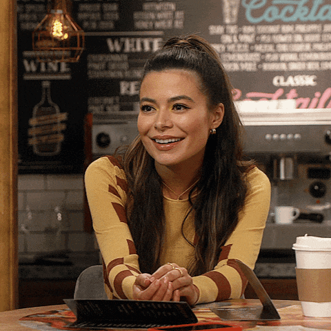 a woman sits at a table in front of a chalkboard that says cocktail
