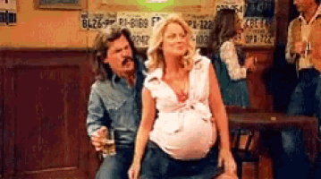 a man and a pregnant woman are sitting at a bar .