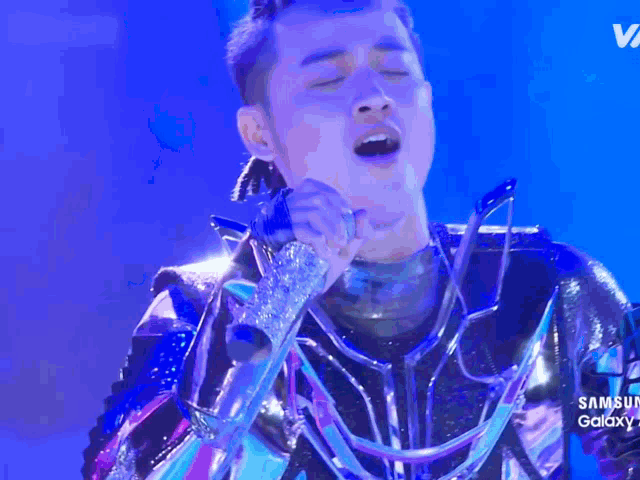 a man singing into a microphone with samsung galaxy on the bottom of the screen