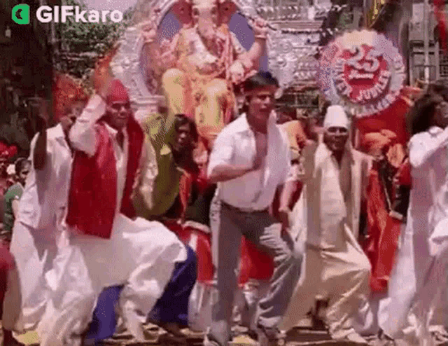 a group of people are dancing in front of a statue of ganesha .