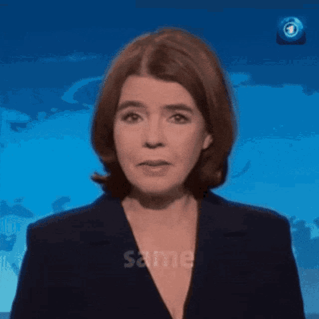 a woman in a blue suit stands in front of a blue background with the word same visible